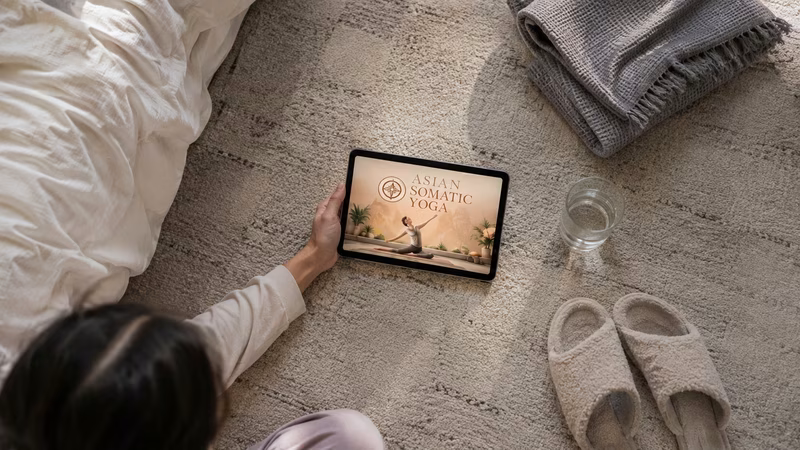 Tablet displaying a somatic yoga video lesson next to a rolled mat.